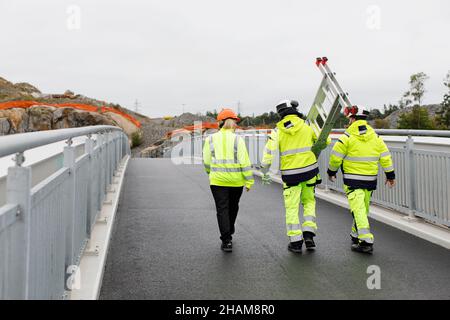 Ingenieure in reflektierender Kleidung gehen auf der Brücke Stockfoto