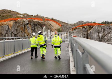 Ingenieure in reflektierender Kleidung gehen auf der Brücke Stockfoto