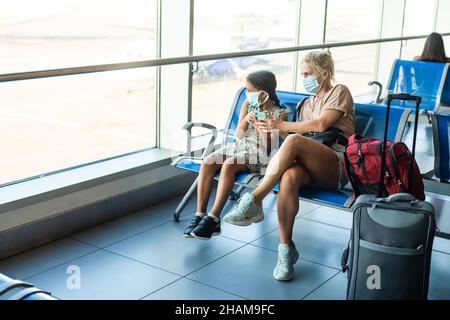 Familie am Flughafen. Attraktive junge Frau und niedliche kleine Tochter sind bereit für die Reise. Glückliches Familienkonzept. Stockfoto