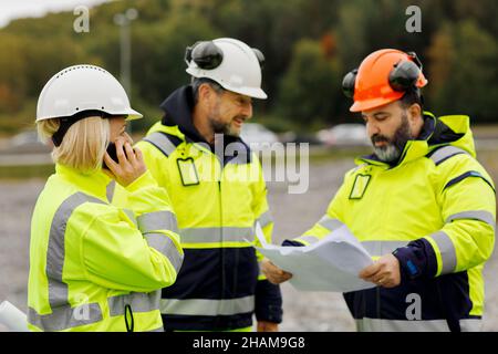 Ingenieure in reflektierender Kleidung diskutieren Pläne Stockfoto