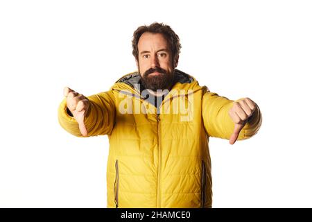 Verwirrt bärtiger Mann Kerl in gelben Casual Jacke isoliert auf weißem Hintergrund, Daumen nach unten Finger Stockfoto