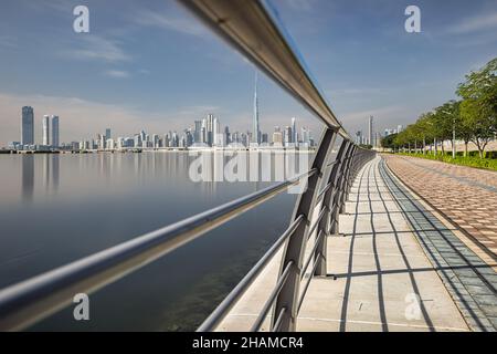 Mittagsaufnahme in Dubai, die die Skyline auf ruhigen Gewässern und Geländern zeigt Stockfoto