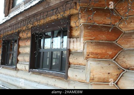 Gemütliches Holzhaus mit hängender Girlande im Wintertag Stockfoto