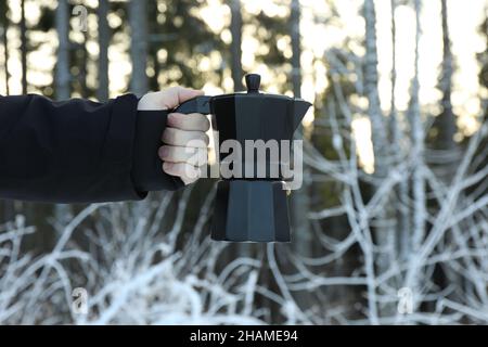 Die männliche Hand hält die Kaffeemaschine im Wald Stockfoto