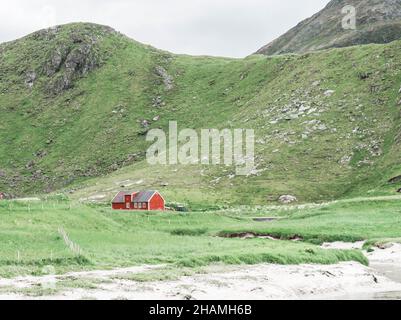 Traditionelles norwegisches Bauernhaus aus rotem Holz, umgeben von Bergen. Haus trennen. Minimale Landschaft Stockfoto