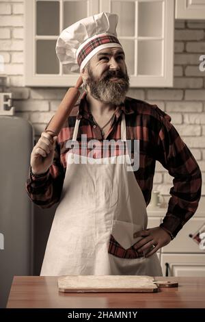 Porträt eines lächelnden männlichen Küchenchefs mit gekochtem Essen, das in der Küche steht. Stockfoto