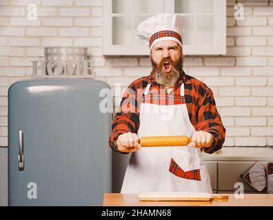 Wütend Koch Bäcker Mann Anheben von Nudelholz bedrohlich in der weißen Küche. Stockfoto