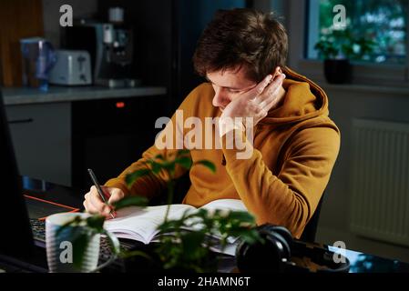 Man arbeitet spät am Heimarbeitsplatz, Remote-Work-Konzept. Burnout und emotionaler Stress aufgrund von Überlastung Stockfoto