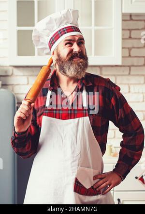 Porträt eines lächelnden männlichen Küchenchefs mit gekochtem Essen, das in der Küche steht. Stockfoto