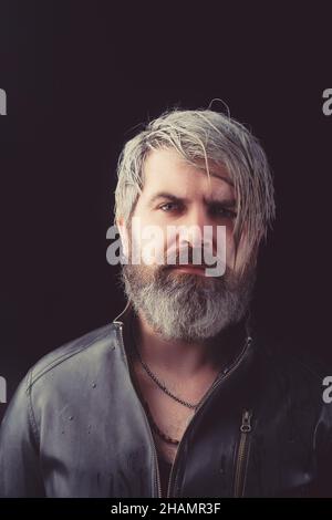 Portrait des brutalen jungen Mannes mit langen nassen blonden Haaren in Lederjacke. Männliche Mode, Beauty-Konzept. Klassischer Style. Studioaufnahme. Stockfoto