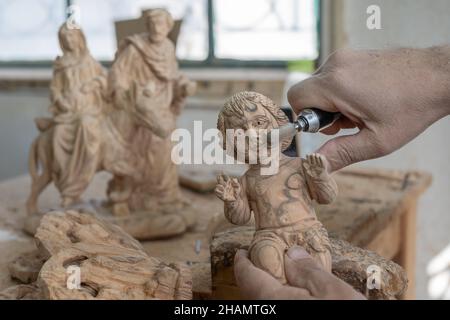 Bethlehem. 14th Dez 2021. Am 14. Dezember 2021 arbeitet ein Bildhauer an einer Olivenholzskulptur für das bevorstehende Weihnachtsfest in einer Werkstatt in der Stadt Bethlehem im Westjordanland. Quelle: Luay Sababa/Xinhua/Alamy Live News Stockfoto