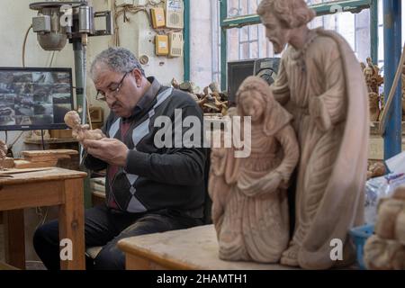 Bethlehem. 14th Dez 2021. Am 14. Dezember 2021 arbeitet ein Bildhauer an einer Olivenholzskulptur für das bevorstehende Weihnachtsfest in einer Werkstatt in der Stadt Bethlehem im Westjordanland. Quelle: Luay Sababa/Xinhua/Alamy Live News Stockfoto