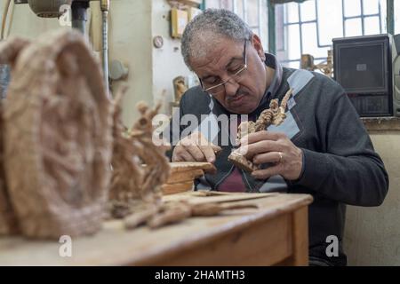 Bethlehem. 14th Dez 2021. Am 14. Dezember 2021 arbeitet ein Bildhauer an einer Olivenholzskulptur für das bevorstehende Weihnachtsfest in einer Werkstatt in der Stadt Bethlehem im Westjordanland. Quelle: Luay Sababa/Xinhua/Alamy Live News Stockfoto