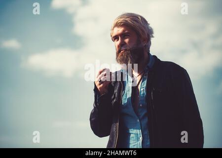 Bärtiger Hipster auf der Spitze des hohen Gebäudes mit Stadtbild im Hintergrund. Stockfoto