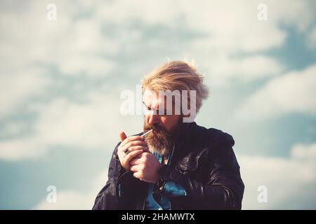 Brutaler Mann mit Bart auf der Oberseite des hohen Gebäudes mit Stadtbild im Hintergrund. Stockfoto