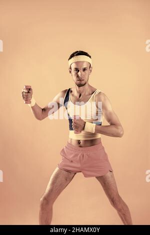 Achtung. Beginne mit dem Training. Nahaufnahme Porträt von verrückten Jugend Mann ziehen kleine rosa Hanteln isoliert auf glänzendes gelbes Hintergrund. Stockfoto