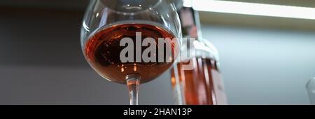 Glas mit gegossenem Alkohol und Flasche befindet sich in der Nähe auf dem Tisch Stockfoto