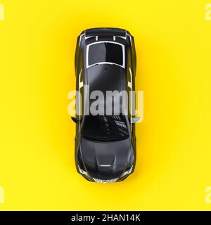 Schwarzes Luxusauto auf gelbem Hintergrund, Draufsicht. 3D Rendern Stockfoto