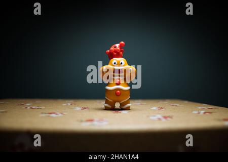 Lebkuchenmann lächelt auf einem Weihnachtsgeschenk mit blauem Hintergrund. Dekoration für Neujahr, Weihnachtsspielzeug Stockfoto