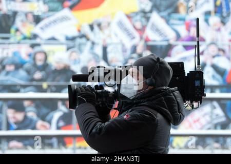 Altenberg, Deutschland. 12th Dez 2021. Rennrodel: Weltmeisterschaft, Team-Staffel. Im Zielbereich steht ein Kameramann vor einer Fotowand. Quelle: Sebastian Kahnert/dpa-Zentralbild/ZB/dpa/Alamy Live News Stockfoto