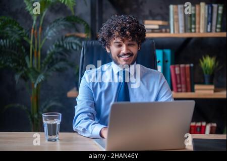 Mann, der am Tisch sitzt und an einem Laptop arbeitet Stockfoto
