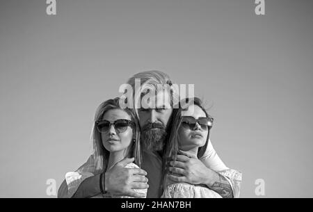 Portrait von glücklichen Mann zwischen zwei Mädchen auf Himmel Hintergrund im Sommerurlaub stehen. Stockfoto