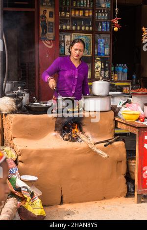 Eine Frau kocht auf einem Chulo oder einem traditionellen Holzofen im Freien aus Schlamm in einem Restaurant am Straßenrand in Malekhu, Nepal. Stockfoto