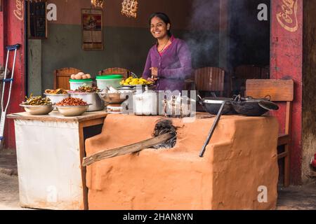 Eine Frau kocht auf einem Chulo oder einem traditionellen Holzofen im Freien aus Schlamm in einem Restaurant am Straßenrand in Malekhu, Nepal. Stockfoto