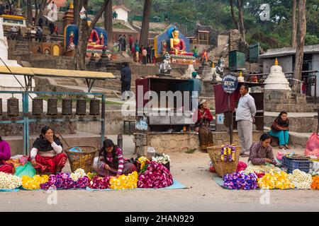 Händler, die Blumengirlanden für religiöse Opfergaben am Eingang des Swayambhunath-Tempelkomplexes in Kathmandu, Nepal, verkaufen. Stockfoto