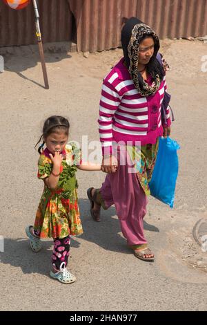 Eine nepalesische Frau geht mit ihrer kleinen Tochter über eine Straße in der mittelalterlichen Stadt Patan in Nepal. Stockfoto