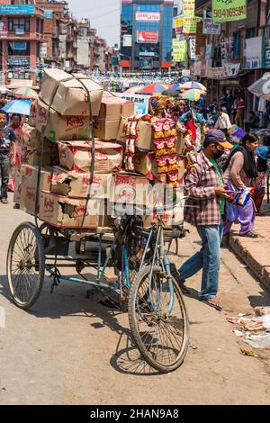 Ein nepalesischer Mann, der in Patan, Nepal, Kartons mit Snackchips auf einem Dreiradwagen trägt. Stockfoto