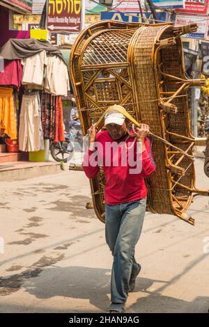 Ein nepalesischer Mann trägt ein schweres Weidensofa auf seinem Rücken mit einer Bauchlinie auf der Straße in Kathmandu, Nepal. Stockfoto