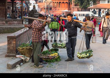 Zwei nepalesische Männer tragen Produkte mit Körben auf Schulterpacken auf dem Durbar Square, Kathmandu, Nepal. Stockfoto