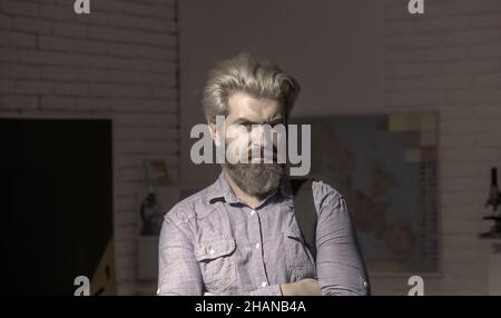 Selbstbewusster bärtiger, hübscher Geschäftsmann in blauem Hemd, der Laptop hält und die Kamera anlächelt. Stockfoto