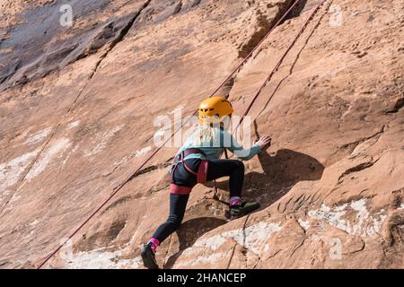 Ein siebenjähriges Mädchen, das im Klettergebiet Wall Street in der Nähe von Moab, Utah, Klettern lernt. Stockfoto