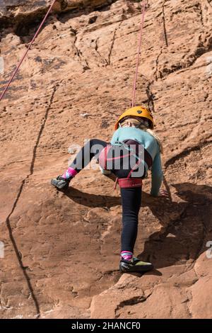 Ein siebenjähriges Mädchen, das im Klettergebiet Wall Street in der Nähe von Moab, Utah, Klettern lernt. Stockfoto