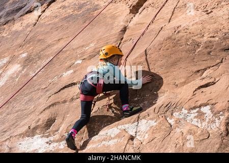 Ein siebenjähriges Mädchen, das im Klettergebiet Wall Street in der Nähe von Moab, Utah, Klettern lernt. Stockfoto