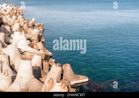 Küstenbrecher schützen vor großen Wellen mit Meeresgrund. Die Küste ist mit Betontetrapoden verstärkt. Stockfoto