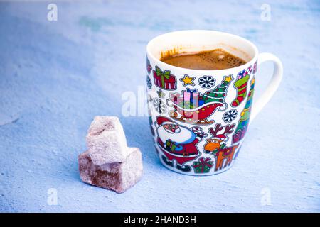 Schwarzer Kaffee in einer Tasse mit Neujahrsmotiv und türkischen Köstlichkeiten auf dem hellen Hintergrund. Stockfoto
