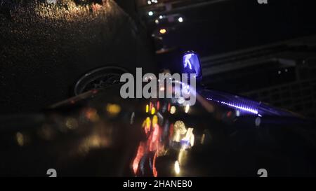 Nachtstadt aus der Rückansicht des Autos. Filmmaterial. Rückspiegel des Autos in der Stadt bei Nacht. Stockfoto