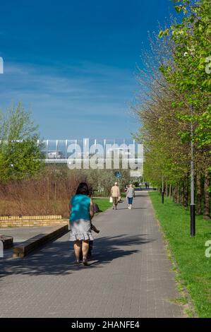 POZNAN, POLEN - 22. Apr 2018: Eine vertikale Aufnahme der Menschen, die auf einem Fußweg neben Bäumen und Gras im Rataje-Park spazieren. Stockfoto