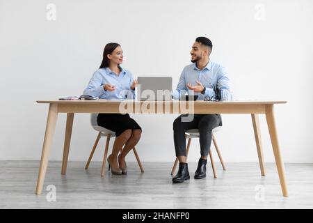 Porträt Lächelnder Kollegen, Die Am Schreibtisch Sitzen Und Sich Unterhalten Stockfoto