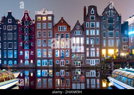 Tanzende Häuser am Amsterdamer Kanal Damrak bei Nacht, Holland, Niederlande Stockfoto