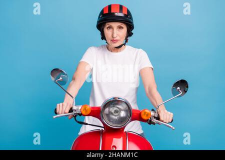 Foto Porträt ältere Frau sitzt auf dem Fahrrad trägt Helm ernsthafte Ruhe isoliert pastellblau Hintergrund Stockfoto
