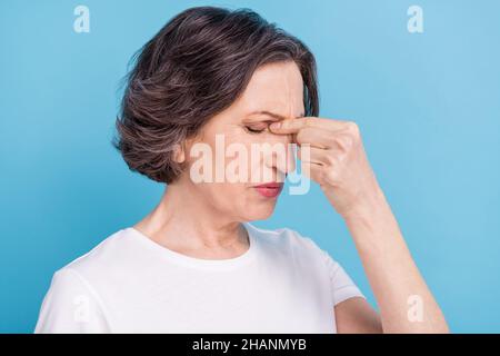 Porträt einer attraktiven frustrierten grauhaarigen Frau, die an einer Krankheit leidet, sich schlecht fühlt, isoliert auf einem lebhaften blauen Hintergrund Stockfoto