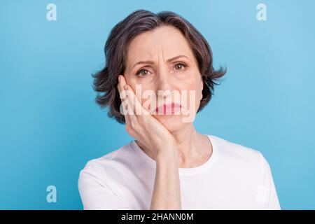 Porträt einer attraktiven depressiven grauhaarigen Frau mit Zahnschmerzen isoliert auf lebhaftem blauem Hintergrund Stockfoto