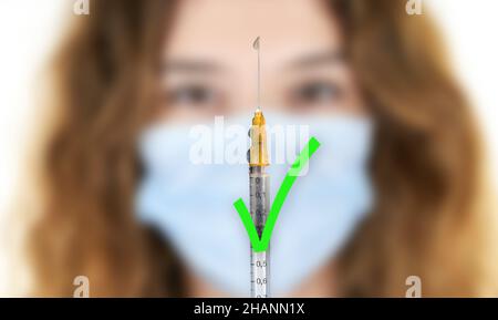 Covid-Impfstoff. Covid-19-Impfstoff. Eine Spritze mit einem grünen Genehmigungssymbol mit einer Frau. Für den Impfstoff. Förderlich für die Impfung Stockfoto