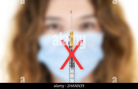 Covid 19-Impfstoff. Eine Spritze mit einem roten Verneinungssymbol und eine Frau. Covid-19 Vax-Schutz. Impfskeptizität. No-Vax. Stockfoto