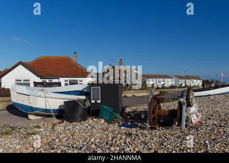 Angelausrüstung und Winde werden am Selsey Beach neben den kleinen hölzernen Fischerbooten in der Nähe der Rettungsbootstation gelagert. Stockfoto