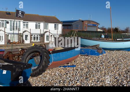 Angelausrüstung, die am Selsey Beach neben den kleinen hölzernen Fischerbooten in der Nähe der Rettungsbootstation gelagert wird. Stockfoto